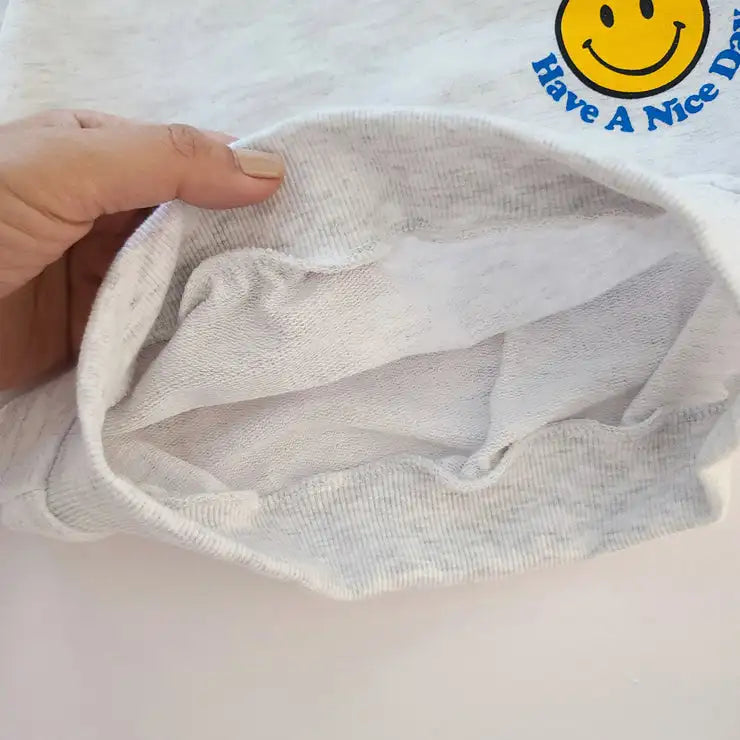 Full shot of toddler smiley face sweatshirt and shorts playwear set on a white background