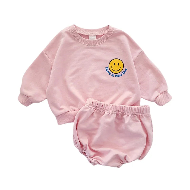 Close-up of the yellow smiley face graphic on the toddler's grey cotton sweatshirt