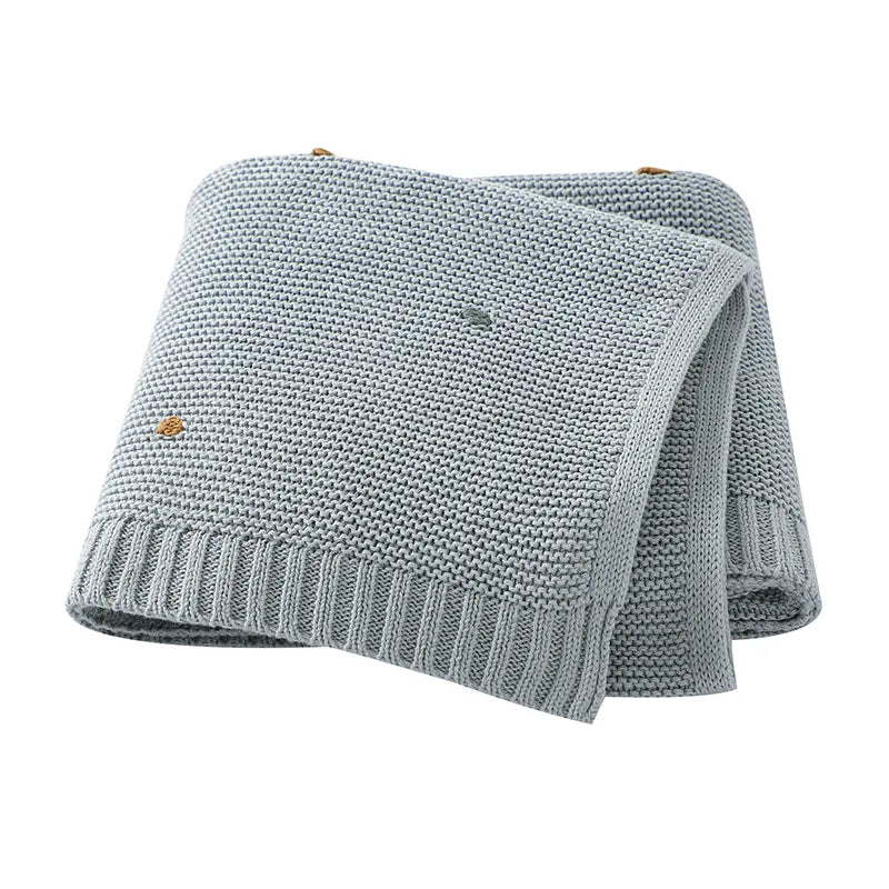 Unisex knitted baby blanket laid flat, showcasing its full size, ideal for strollers and cribs