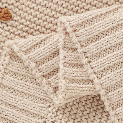 Knitted baby blanket draped over a crib, highlighting its soft texture, perfect for infant bedding
