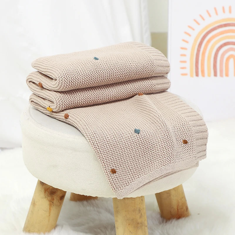 Smiling baby comfortably wrapped in an ultra-soft knitted blanket, a cozy newborn essential