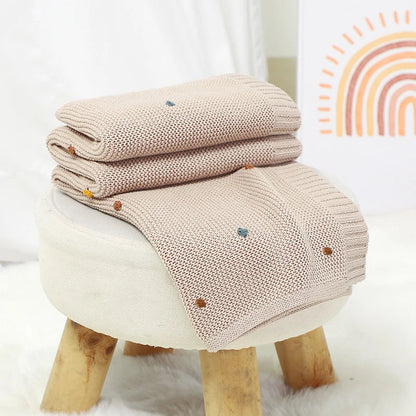 Smiling baby comfortably wrapped in an ultra-soft knitted blanket, a cozy newborn essential