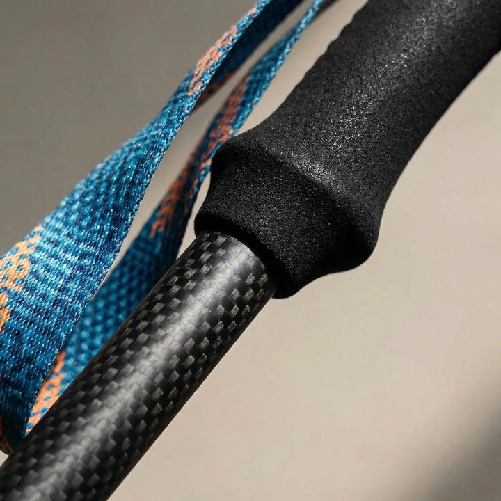 Ergonomic grip of carbon fiber trekking poles used for trail hiking, providing comfort and stability.