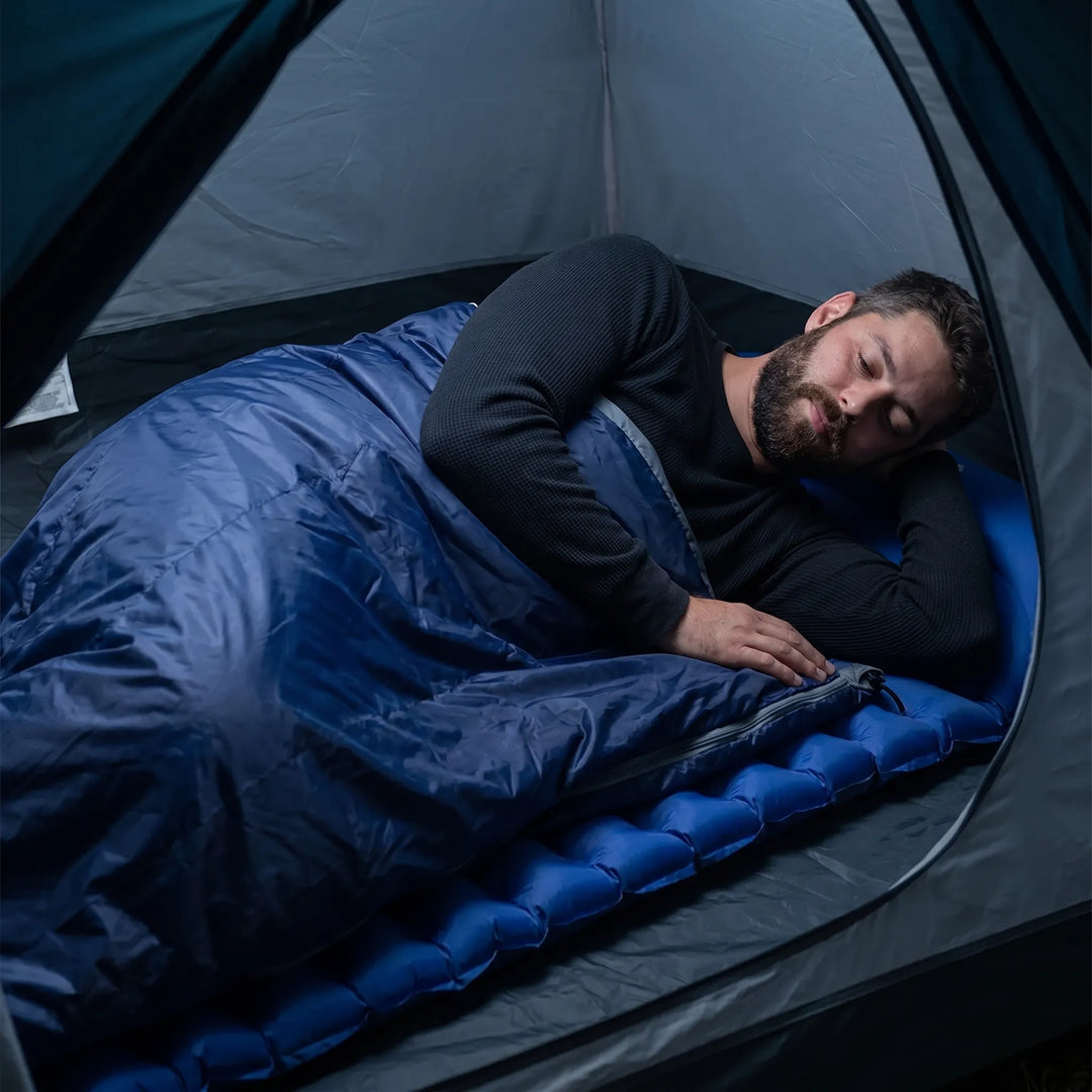 Person holding a compact, ultralight summer sleeping bag, perfect for travel & outdoor gear.