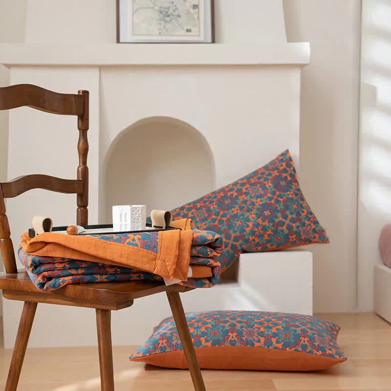 Unisex six-layer cotton quilt draped on a bed, showcasing its vibrant orange & blue pattern and comfortable appeal.