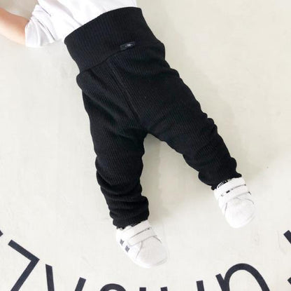 Stack of folded ribbed cotton fleece-lined pants in various sizes, unisex baby clothes collection.