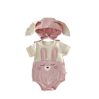 Flat lay of white cotton baby bodysuit onesie and cap on a wooden surface, soft baby clothing.