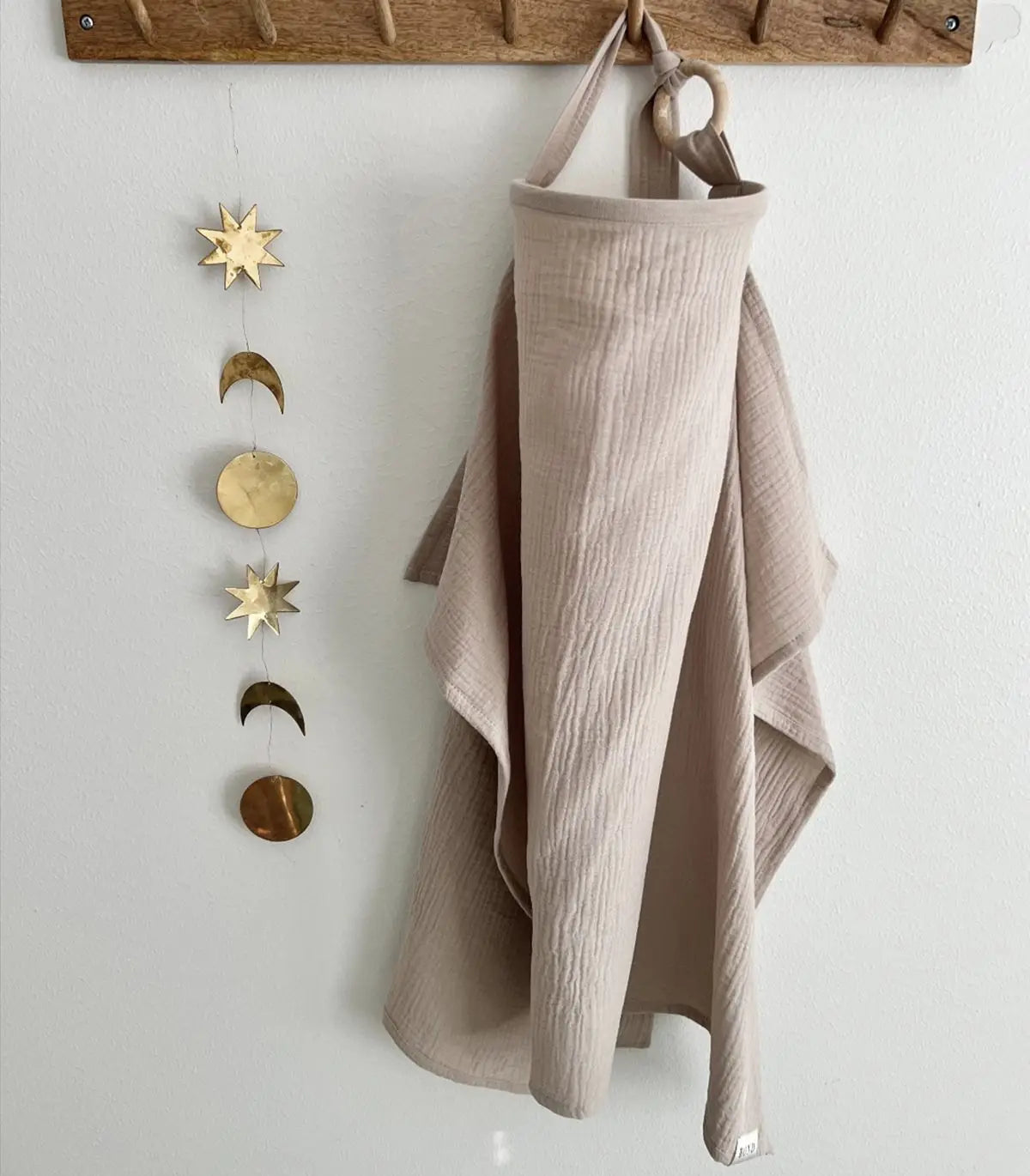 Soft cotton muslin nursing cover with baby peeking out, used for discreet feeding.