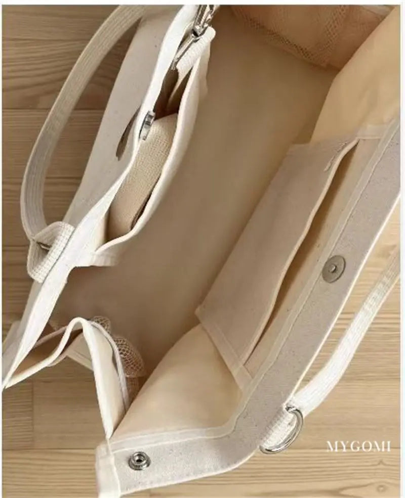Compact white canvas mommy bag, perfect for carrying bottles, diapers, and wipes.