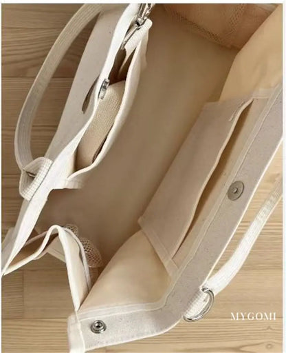 Compact white canvas mommy bag, perfect for carrying bottles, diapers, and wipes.