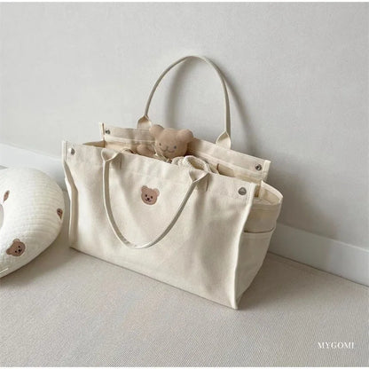 Top view of a white canvas diaper bag organizer, neatly packed with baby accessories.
