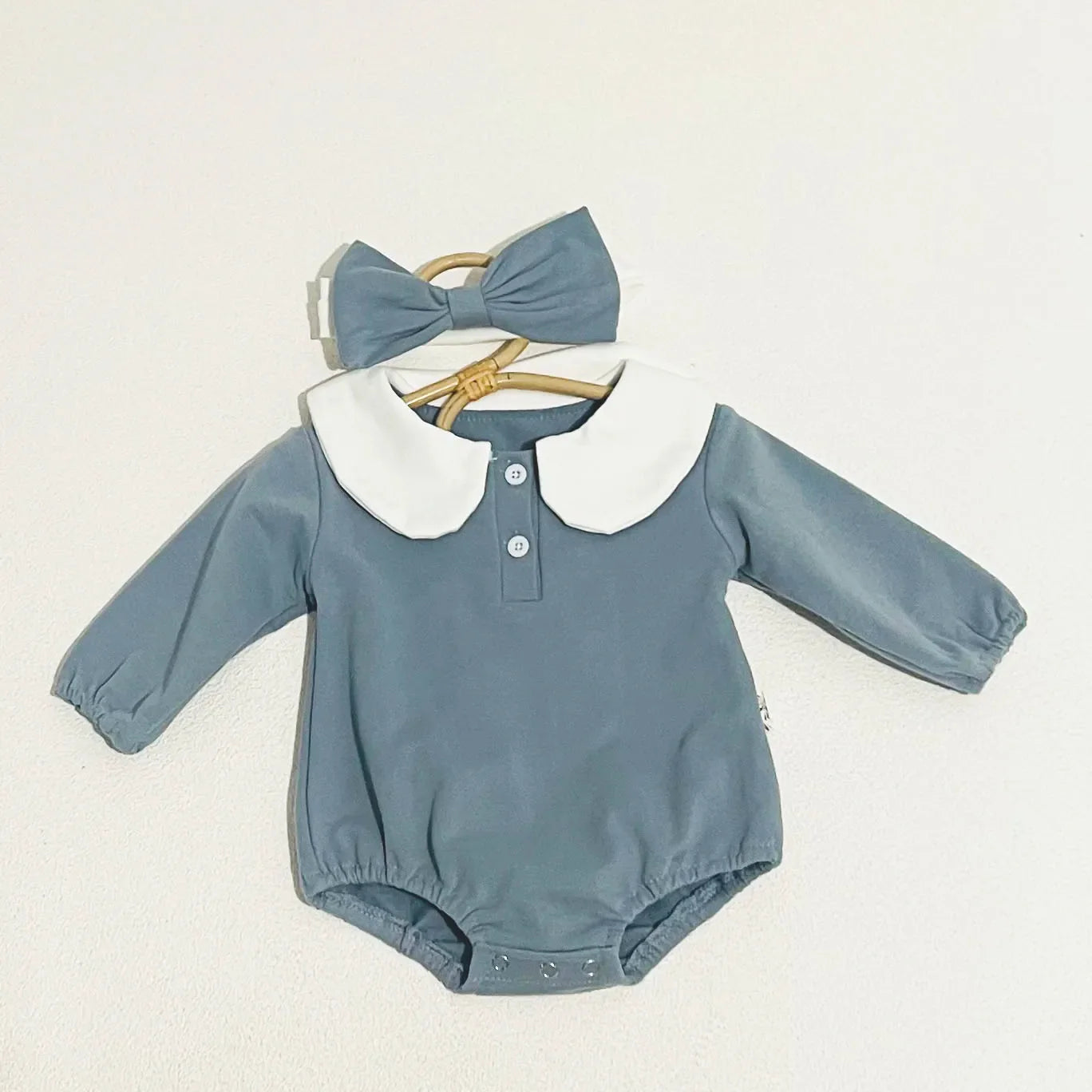 Close-up of a baby bodysuit's Peter Pan collar, delicate stitching on cotton fabric