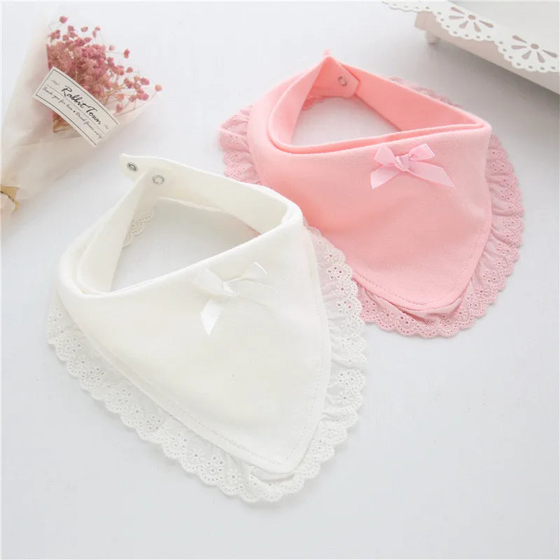 Close-up of a white cotton baby bib with elegant lace trim, highlighting the soft fabric and delicate design.