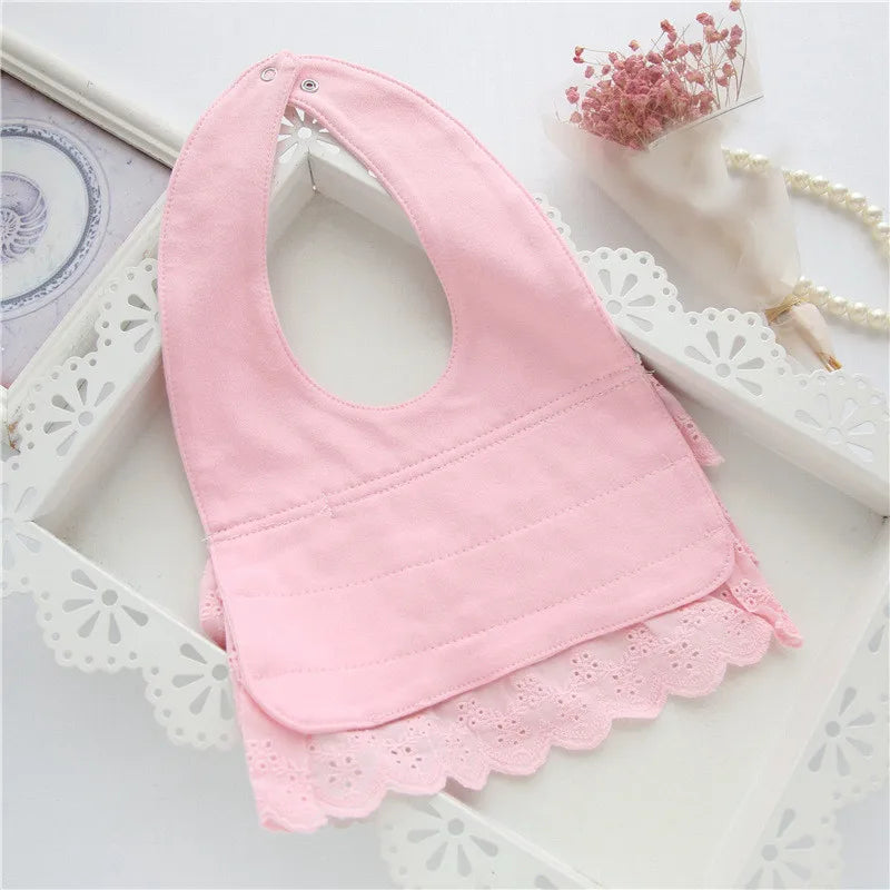 Infant girl wearing a stylish pink cotton lace baby bib, showcasing its comfortable fit and cute appearance.