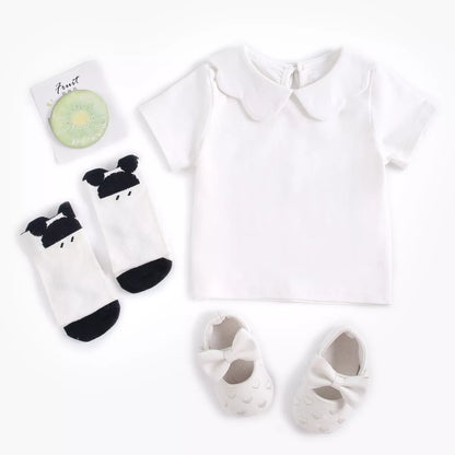 Baby girl playing happily in a comfortable white cotton short sleeve top