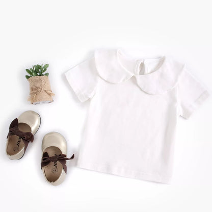 Newborn baby in a pure white cotton top, gentle and soft infant clothing