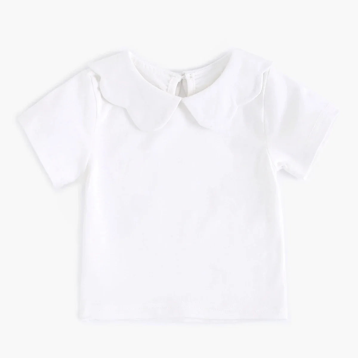 Zoomed-in view of the hem of a white cotton baby fashion top, quality finish