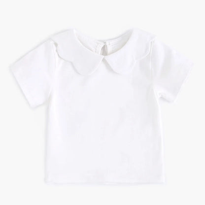 Zoomed-in view of the hem of a white cotton baby fashion top, quality finish