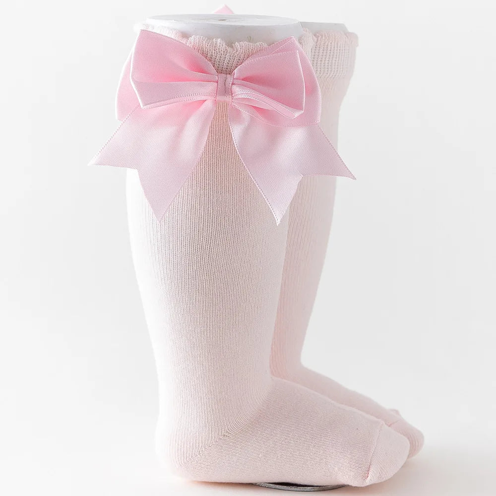 Patterned pink knee-high socks and big solid pink bow, cozy cotton blend toddler socks.