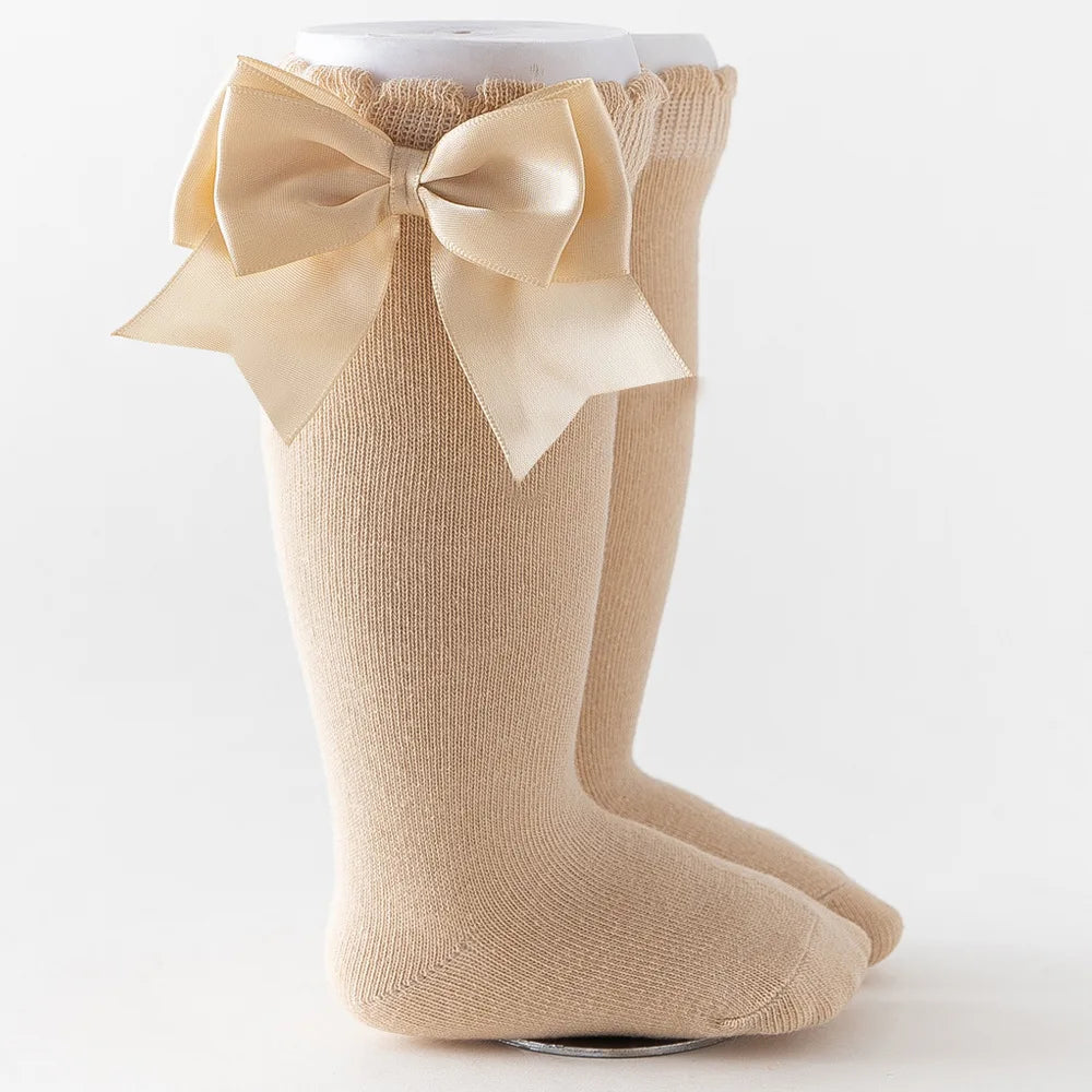 Orange knee-high socks featuring a large metallic bow, adding flair to kids accessories.