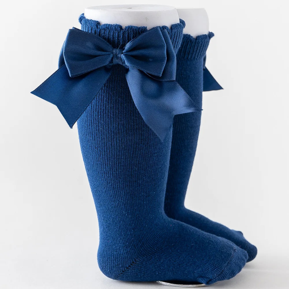 Striped knee-high socks for girls, prominent solid-colored bow, vibrant kids' style.