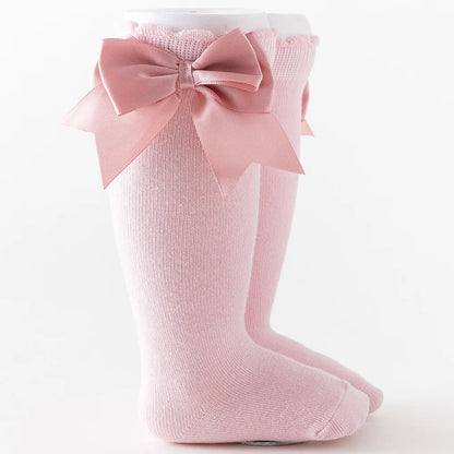 Unicorn-themed knee-high socks with a glittery rainbow bow, magical baby accessory.