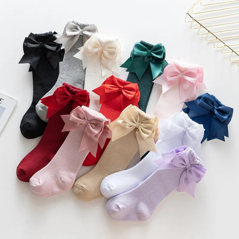 Pink knee-high socks for toddlers with big white satin bow, comfortable and stylish.