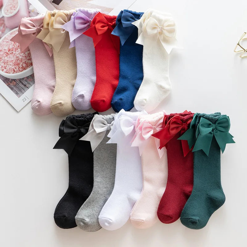 Cute red knee-high girls' socks featuring a large matching bow, ideal for baby accessories.
