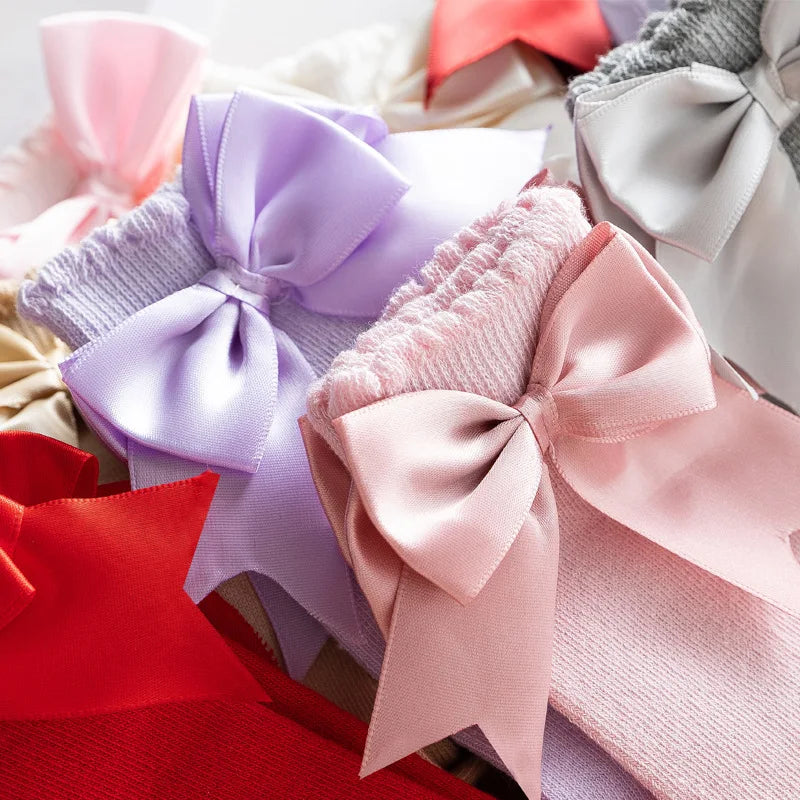 Cream knee-high socks for kids 2-4 years, with oversized black bow, perfect for autumn.