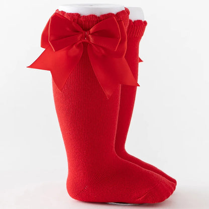Yellow knee-high socks with a big contrasting orange bow, playful design for baby outfits.