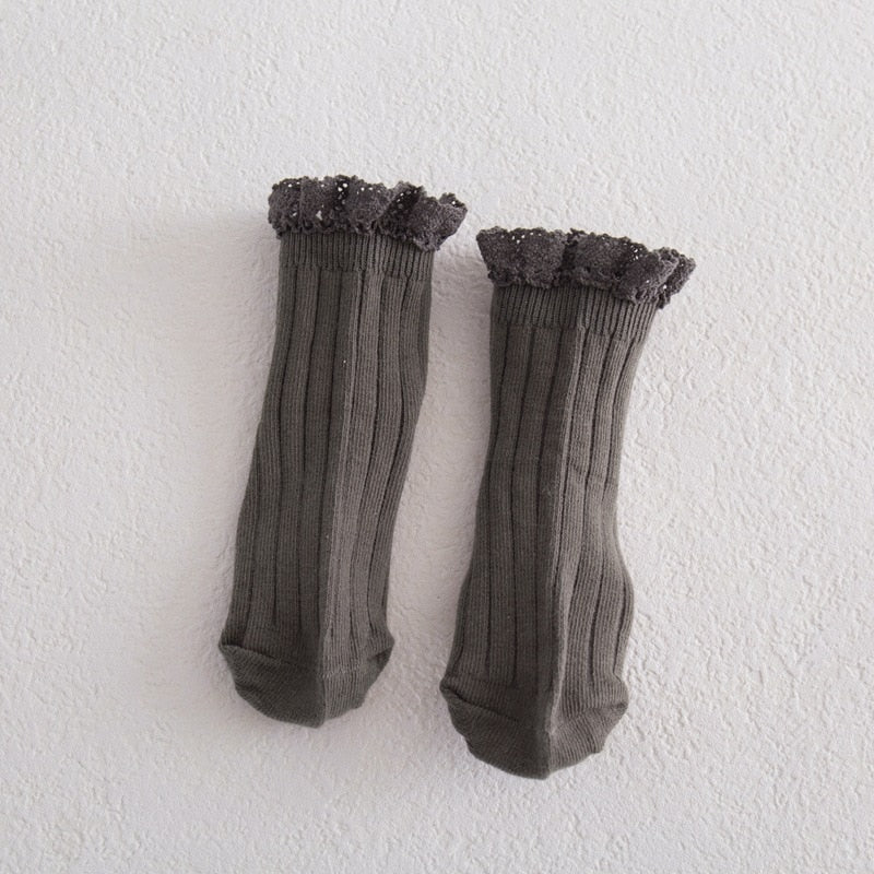 Close-up of white girls' lace frilly ankle socks, showing intricate lace and soft cotton texture