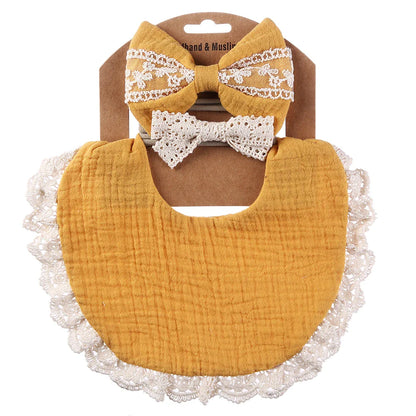 Stylish baby accessory set featuring a soft white muslin bib and a delicate white lace headband for newborns.