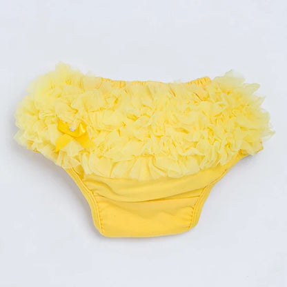 Close-up of ruffled detail on a white cotton blend diaper cover for infants, soft baby bottoms