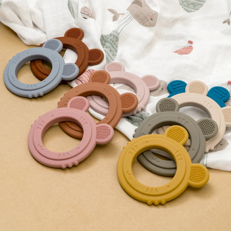 Baby reaching for a soft green silicone rabbit teether, stimulating hand-mouth coordination