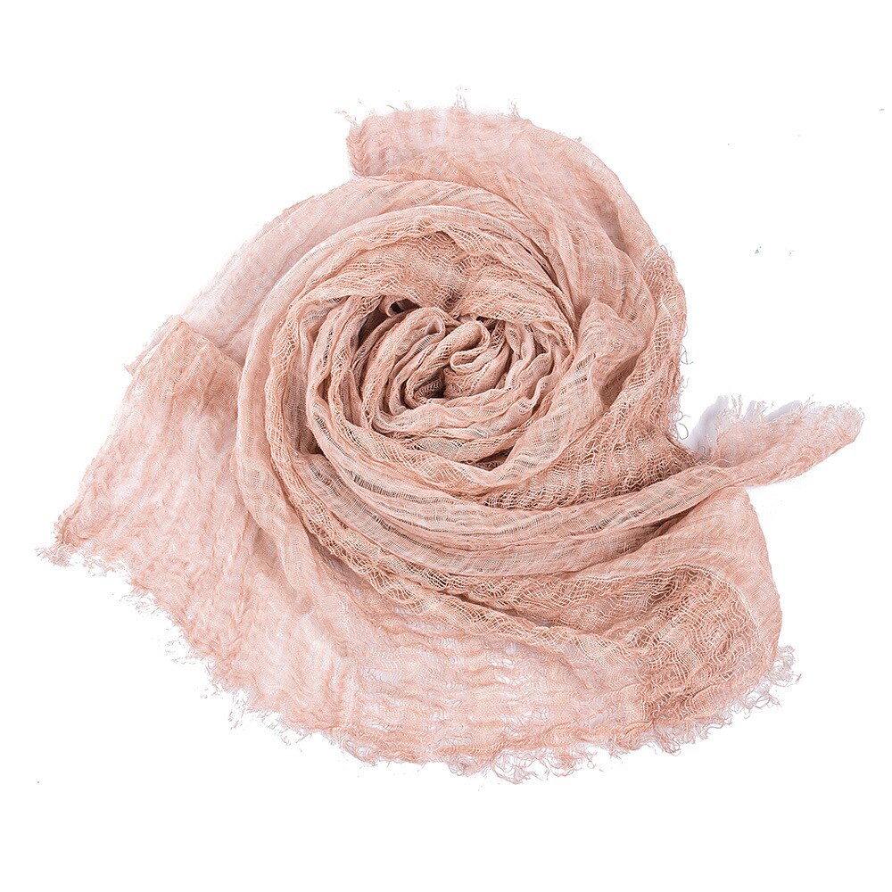 Close-up of a baby's hand gently touching a soft cotton swaddling blanket texture.