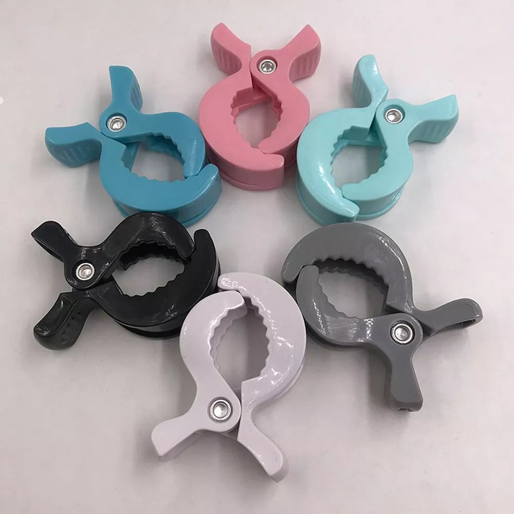 Two white stroller hooks demonstrate secure blanket attachment to a pram handle