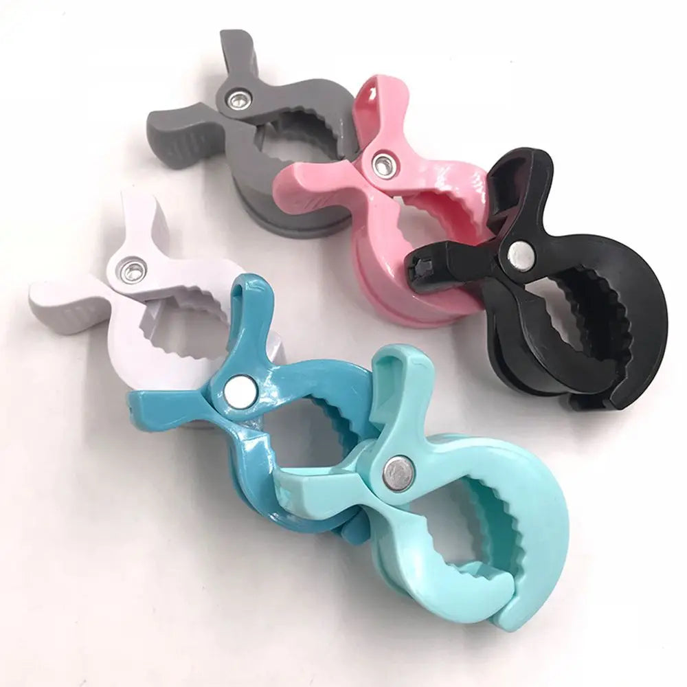 Close-up of a white stroller clip, showing secure grip for baby blankets