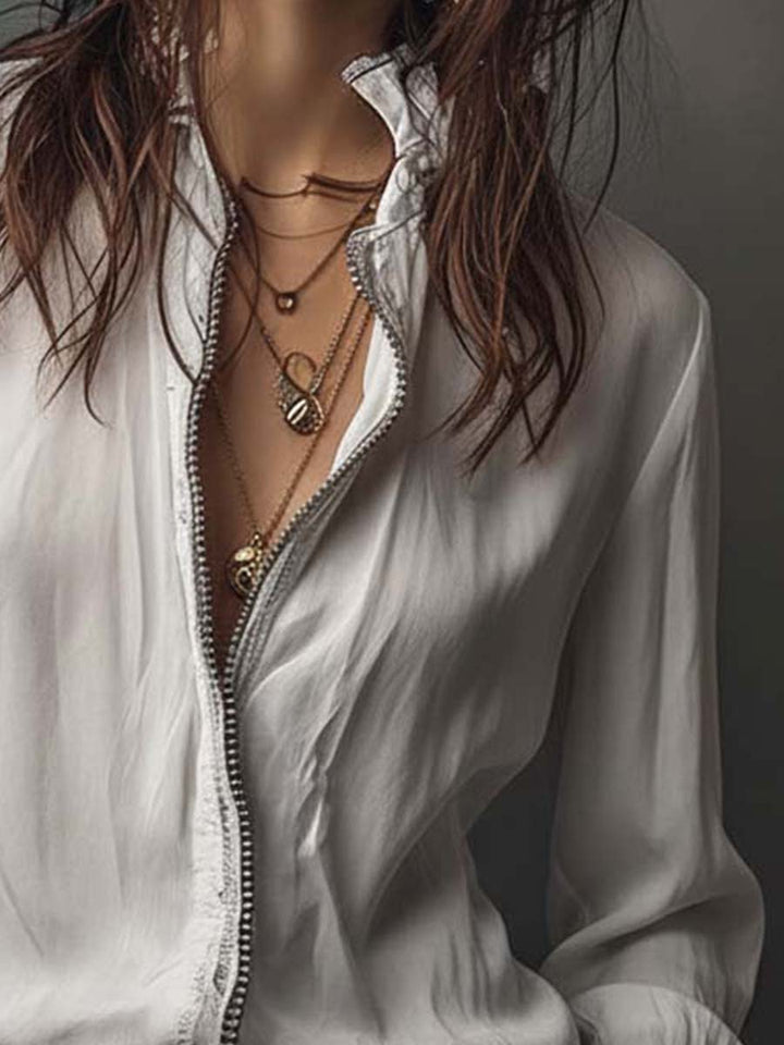 Modern white zip-front women's blouse featuring a stand collar & elegant bell cuff detail. Fashion forward.