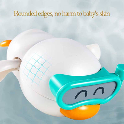 Toddler playing with a wind-up swimming duck bath toy in a bathtub