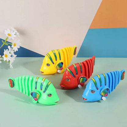 Close-up of a smiling child playing with a wiggling wind-up fish toy