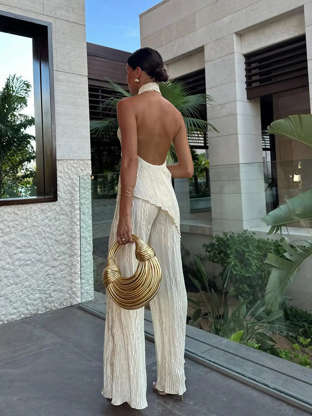 Beige matching two-piece set for women, featuring a halter neck top & pleated wide-leg pants. Summer elegant wear.