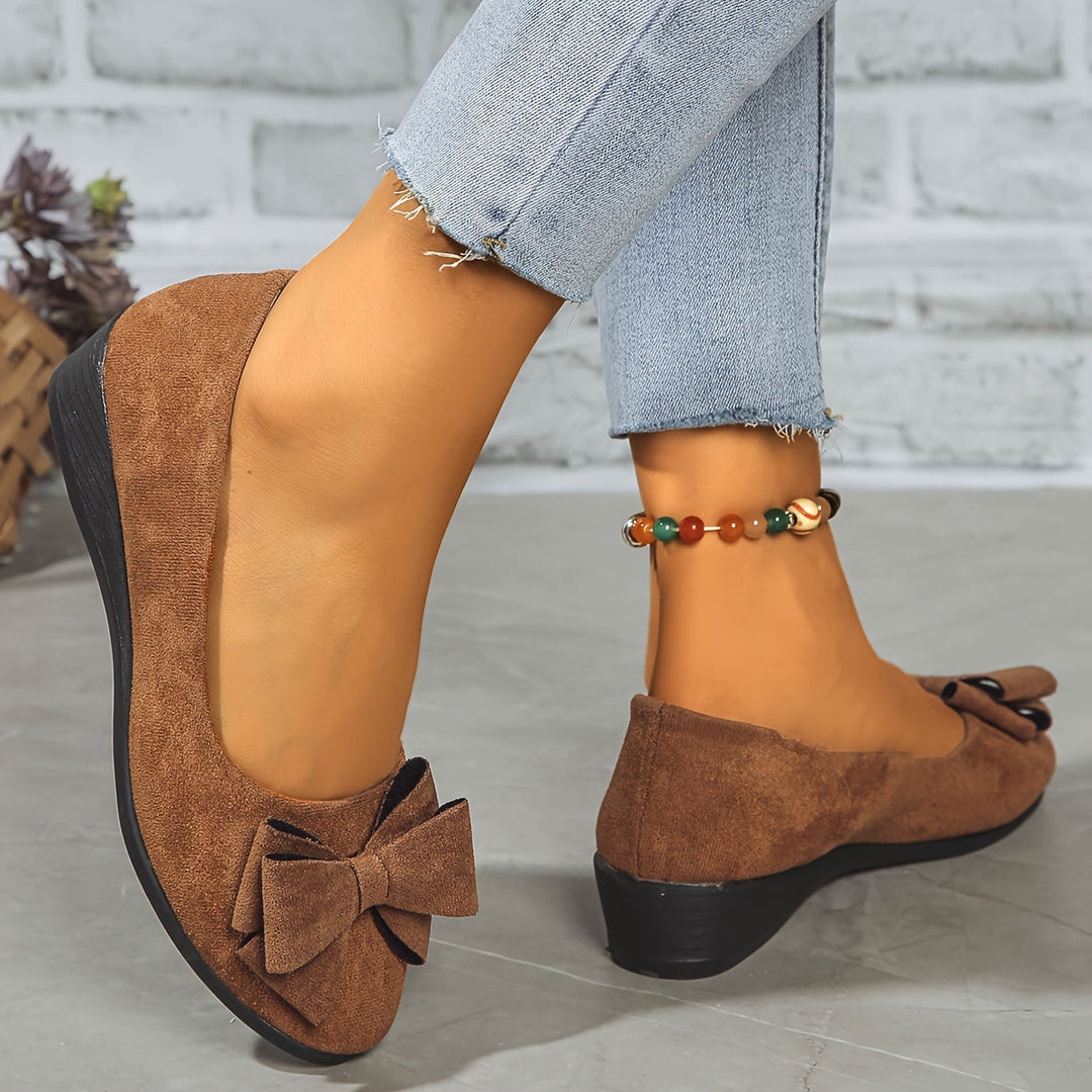 Chic women's ballet flats with prominent bow, round toe and subtle wedge heel.