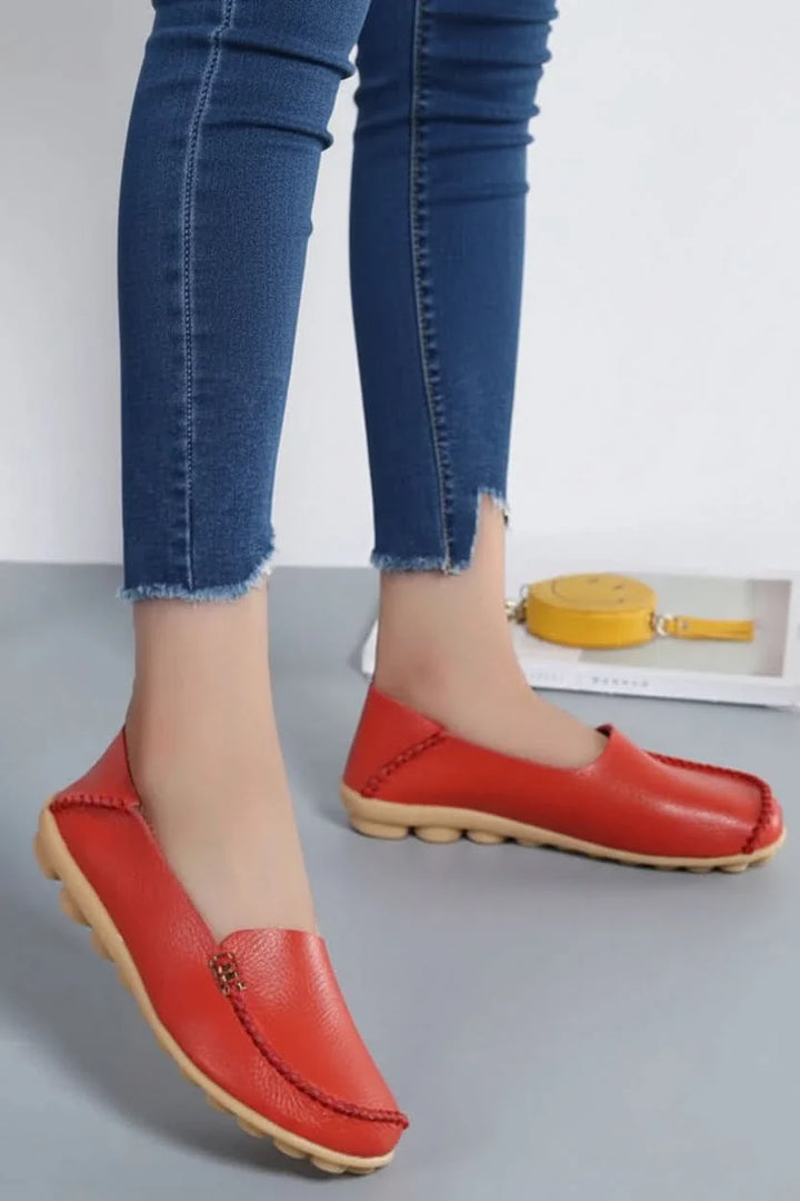Side view of women's red cushioned round-toe flats, designed for supreme comfort & versatile everyday style.