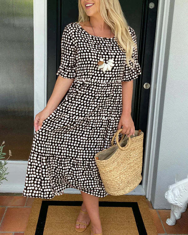 Model wears a versatile women's dotted midi dress, showcasing its relaxed fit and elegant tiered flowy style.