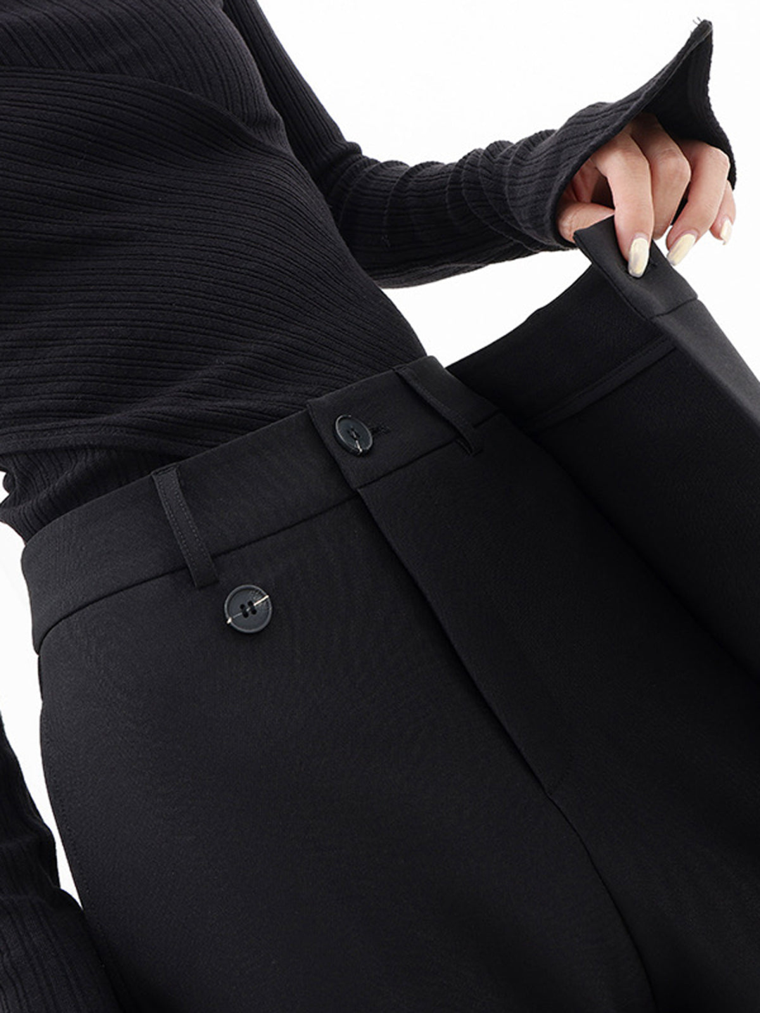 Woman models black Monroe Baggy Trousers, relaxed fit, wide leg, and asymmetric detail for trendy casual look.