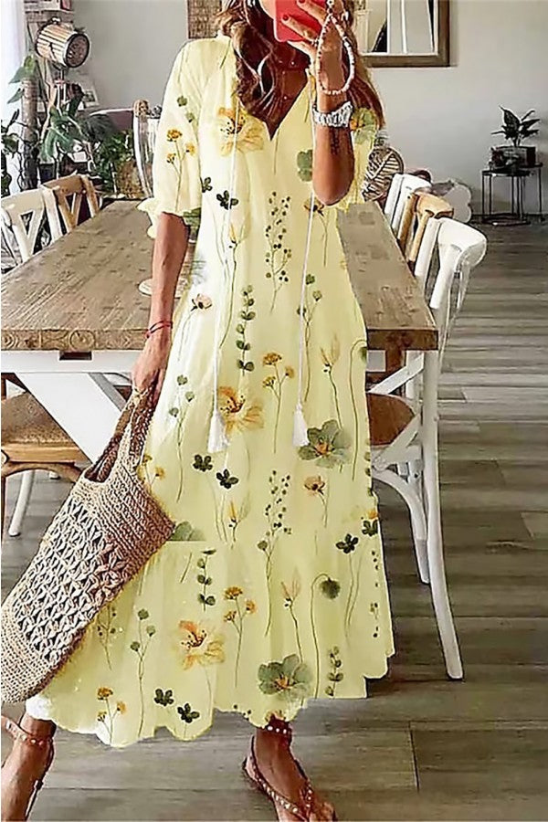 Casual women's long boho maxi dress with a vibrant floral pattern and V-neckline featuring tassels.
