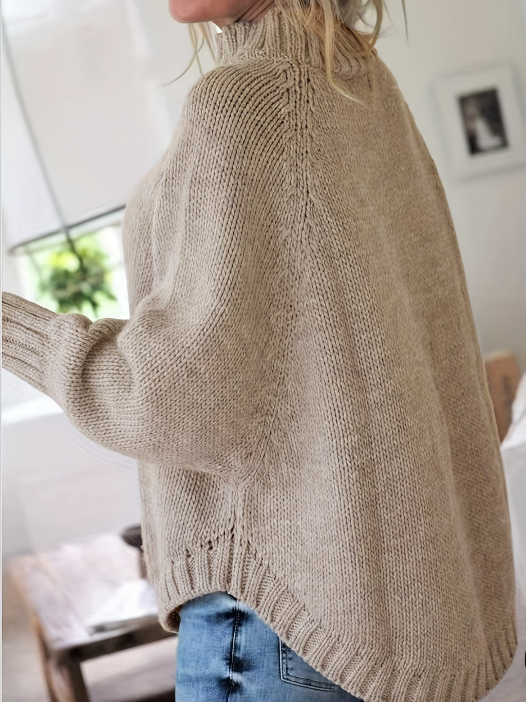 Warm women's cable knit high-neck sweater with a fashionable flared hem, essential fall winter wear.