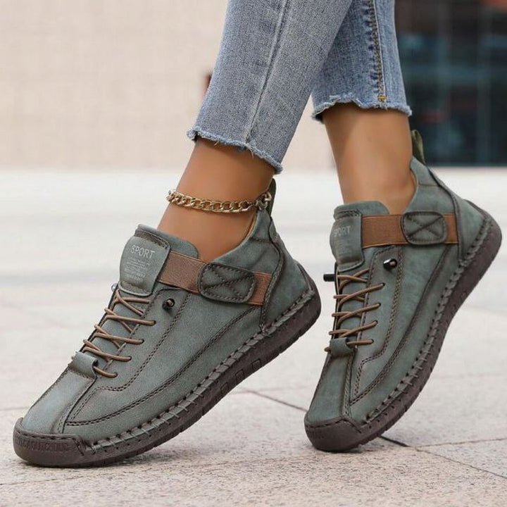 Stylish women's low-top sneakers featuring a secure lace-up closure and decorative stitched accents.