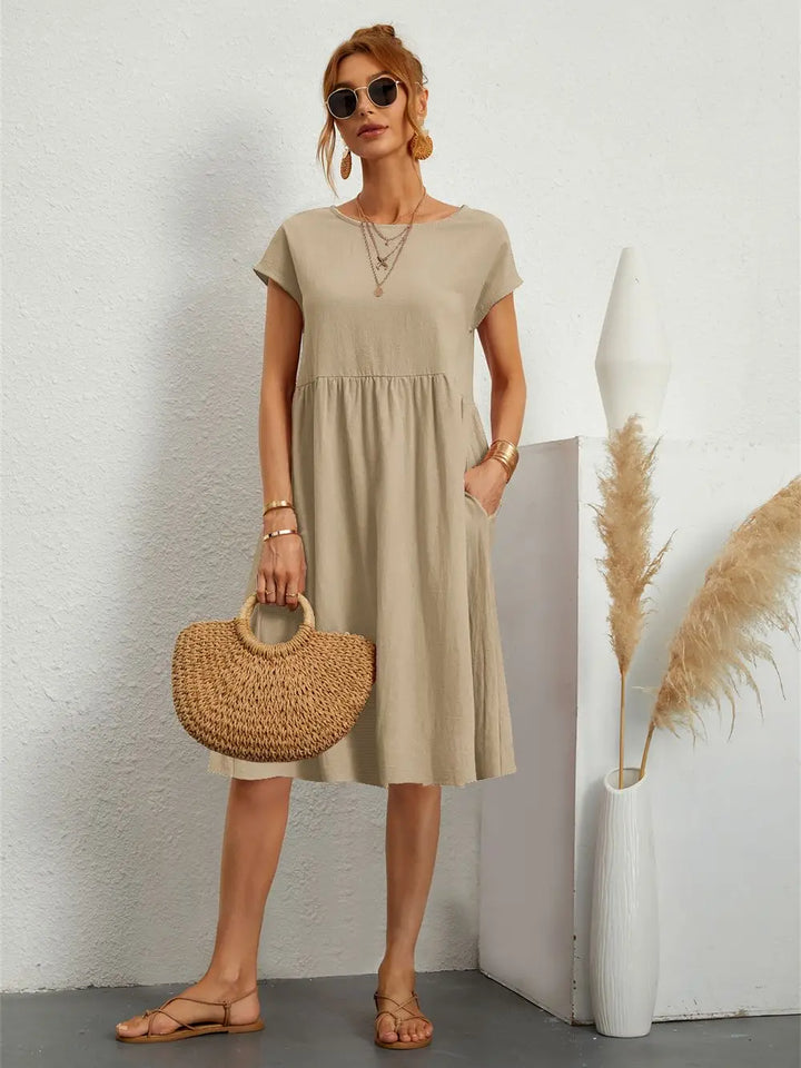 Woman wearing a comfortable casual midi dress with pockets & short sleeves, relaxed summer style.