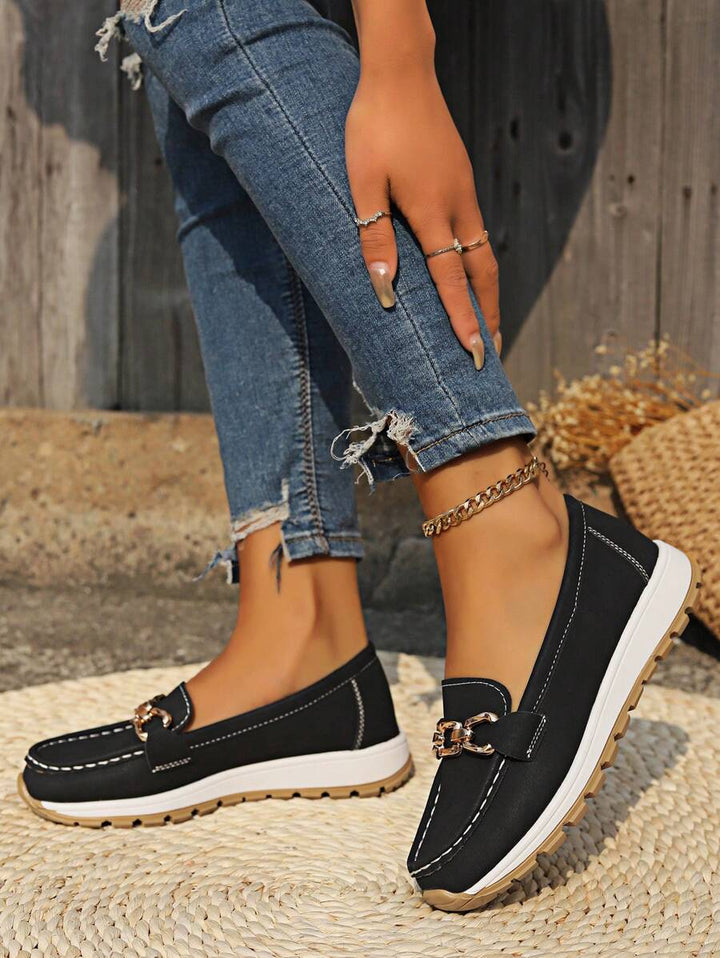 Full shot of women wearing comfortable black flatform loafers with a chic gold chain, perfect for any outfit.